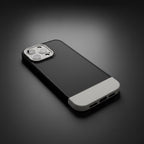 iPhone 14 Pro Max black and white case lying on dark surface - angled lifestyle shot