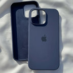 iPhone 15 navy blue silicone case with box on white satin fabric in sunlight - top view