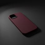 iPhone 14 red silicone case on phone leaning on dark grey textured surface - lifestyle shot